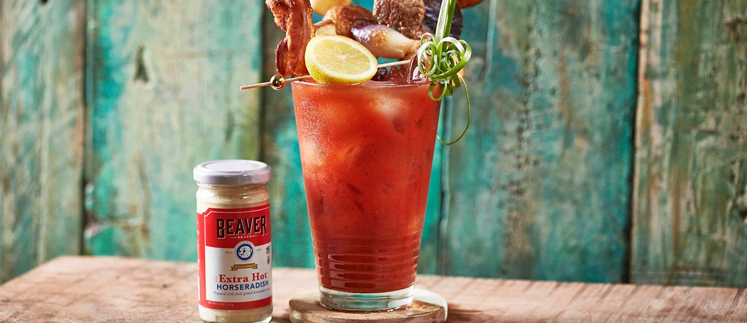 Iced bloody mary topped with lemon, bacon, steak, and onions, plus Beaver Brand Extra Hot Horseradish