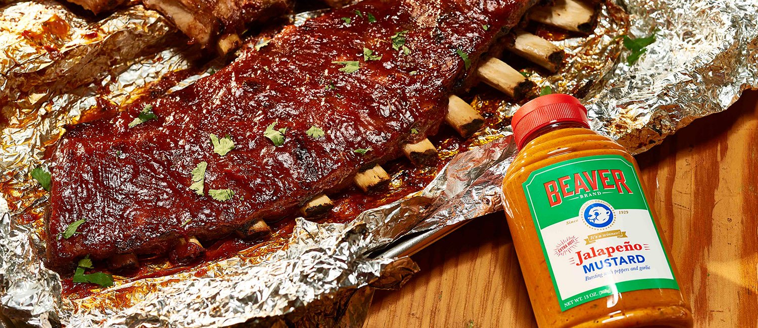 Rack of ribs on foil with Beaver Brand Jalapeño Mustard